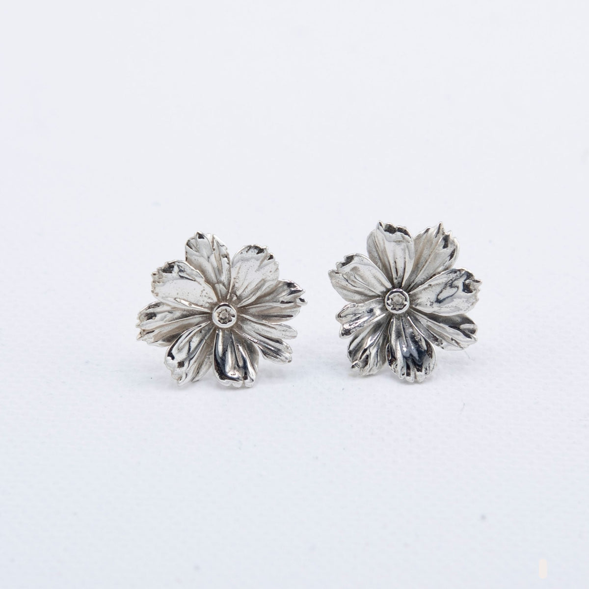 Hand-cast sterling silver Cosmos flower earrings with detailed petal texture, handmade jewellery by RHYN, made in Cape Town.