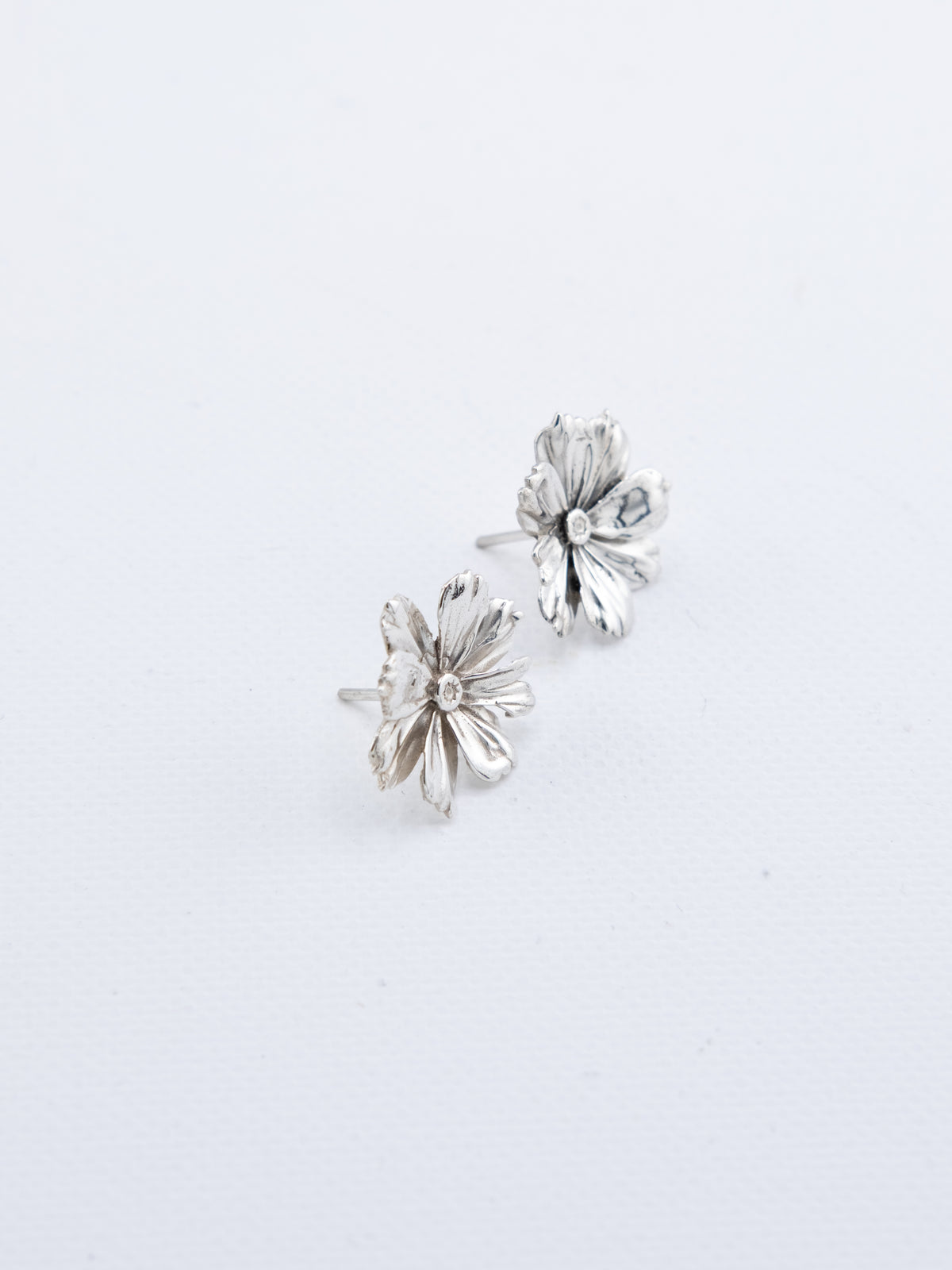 Hand-cast sterling silver Cosmos flower earrings with detailed petal texture, handmade jewellery by RHYN, made in Cape Town.